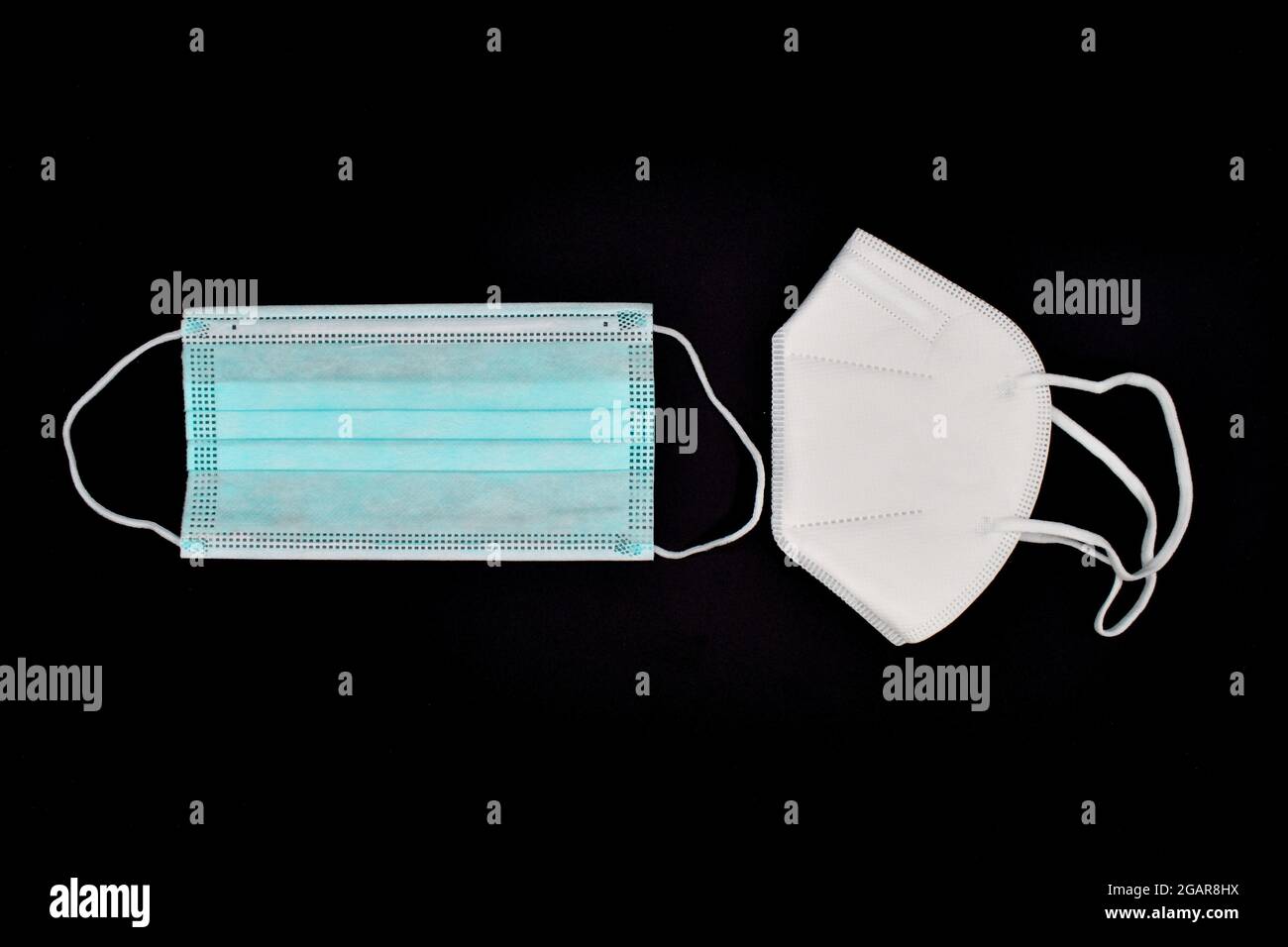 Einweg-KN-95-Maske im Vergleich zu dünner OP-Maske. COVID-19-Prävention. H1N1-, H5N1-Sicherheitsmaßnahmen. Isoliert auf schwarzem Hintergrund. Stockfoto