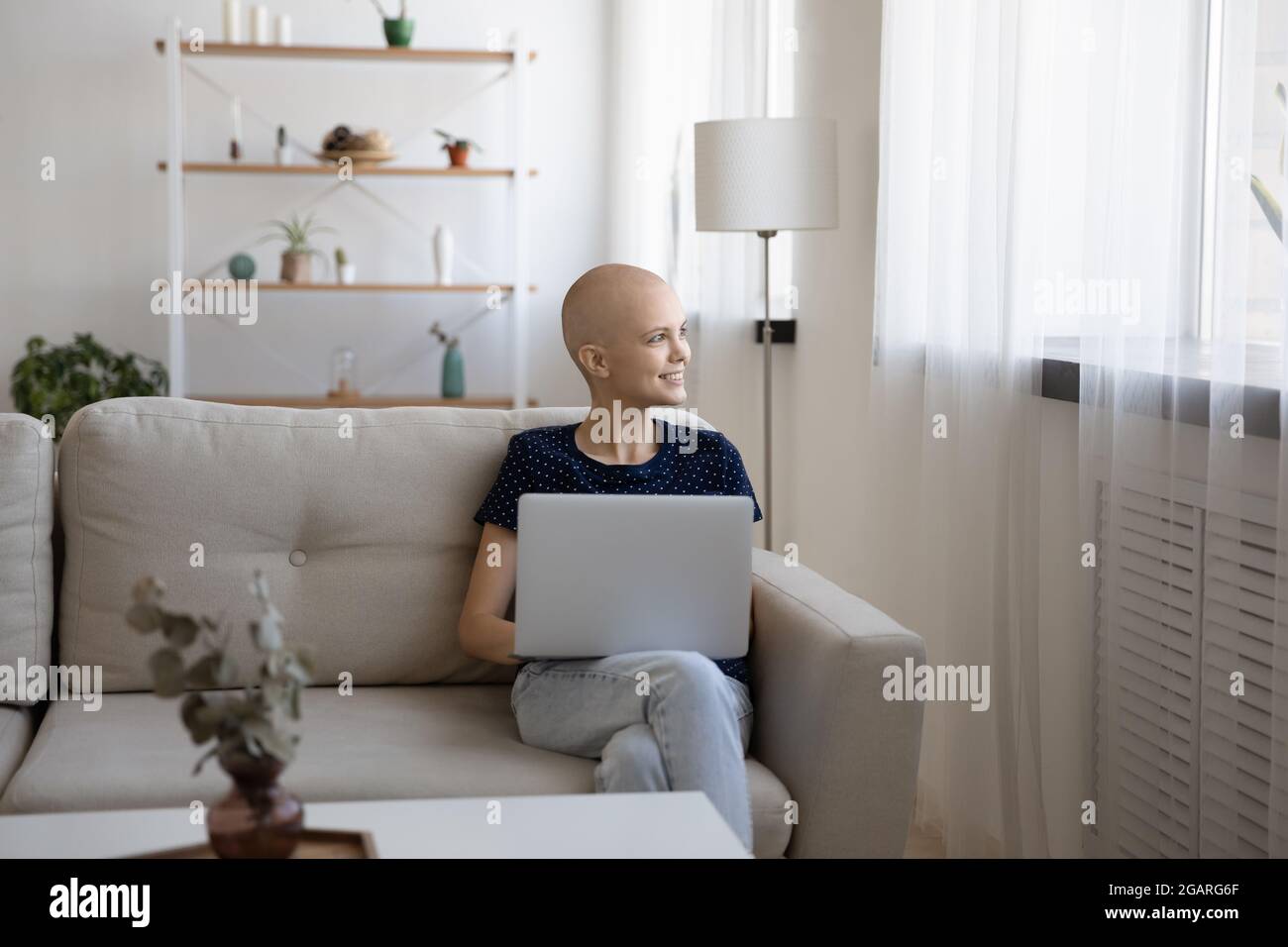 Verträumt jung entspannt haarlos sitzen zu Hause mit Computer. Stockfoto