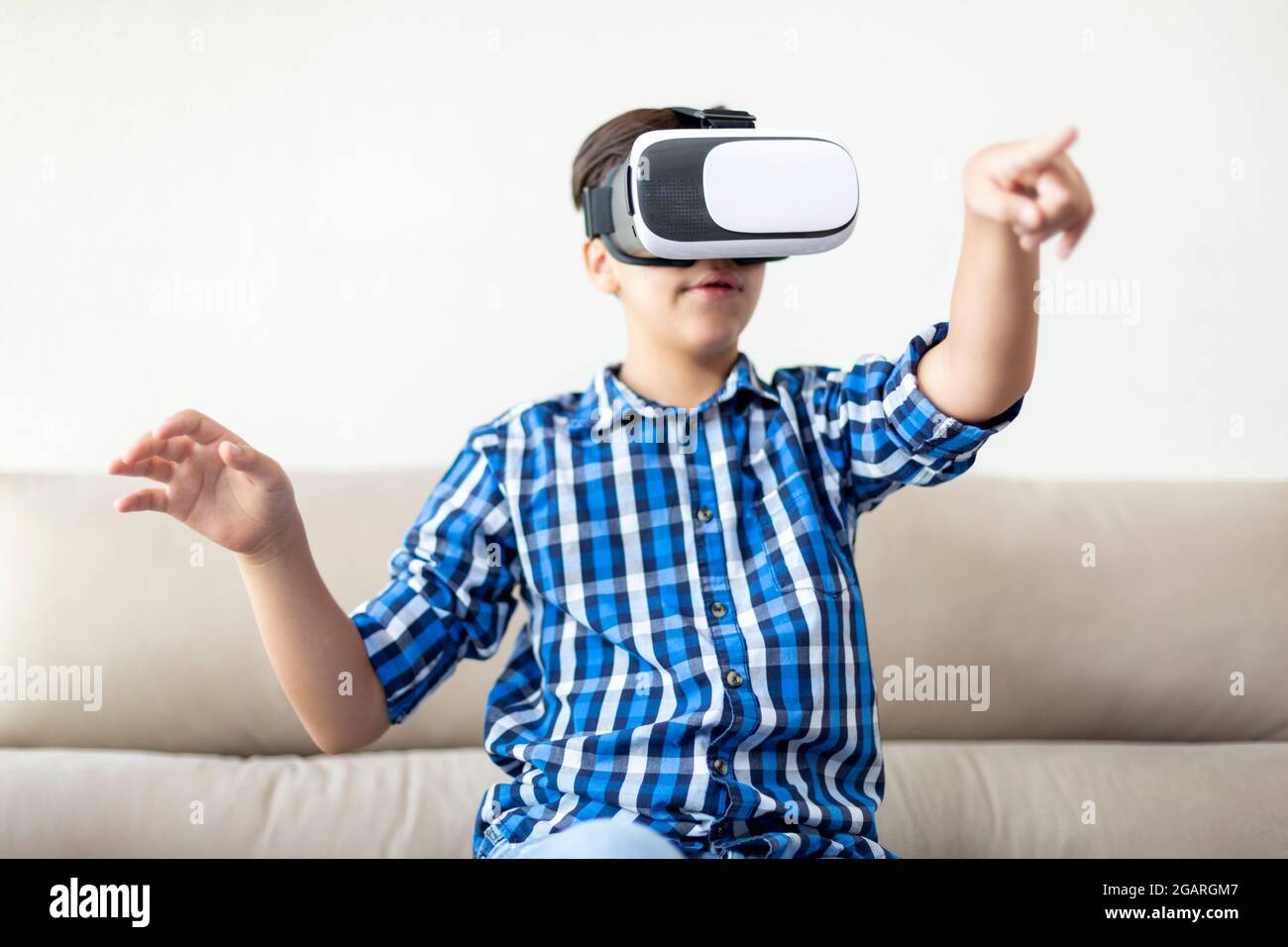 Teenager mit VR-Brille, die seine Arme bewegt und gestikiert. Konzept der neuen Technologien zu Hause. Stockfoto