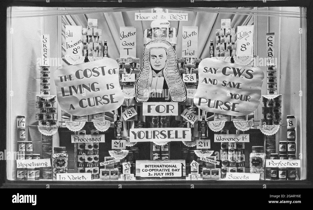 Eine Ausstellung mit 1955 Fenstern in einem Kooperativen-Geschäft in Sheffield, South Yorkshire, England, Großbritannien. Sie feiert ‘International Co-operative Day’ am 2. Juli dieses Jahres. Ein reimender Vers betont die hohen Lebenshaltungskosten und dass Einsparungen bei der Co-op (CWS oder Co-operative Wholesale Society) erzielt werden könnten. Eine Illustration eines Richters ist Teil des Slogans ‘Richter für dich selbst’. Auf dem Display sind Dosen und Dosen von Lebensmitteln zu sehen – ein altes Foto aus den 1950er Jahren. Stockfoto