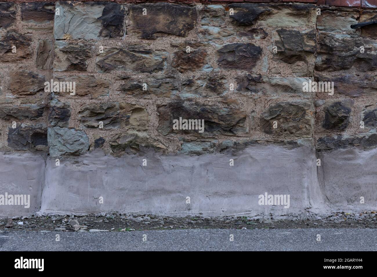 Wand aus sehr variablem Kalkstein mit Betonsockel, kreativer Kopieraum, horizontaler Aspekt Stockfoto