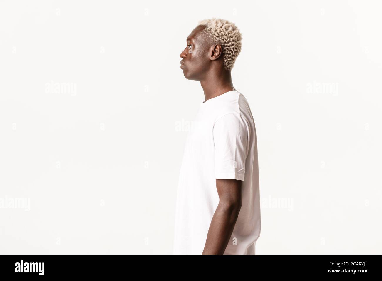 Profil von ernst aussehenden afroamerikanischen blonden Mann, der links, stehend über weißem Hintergrund Stockfoto