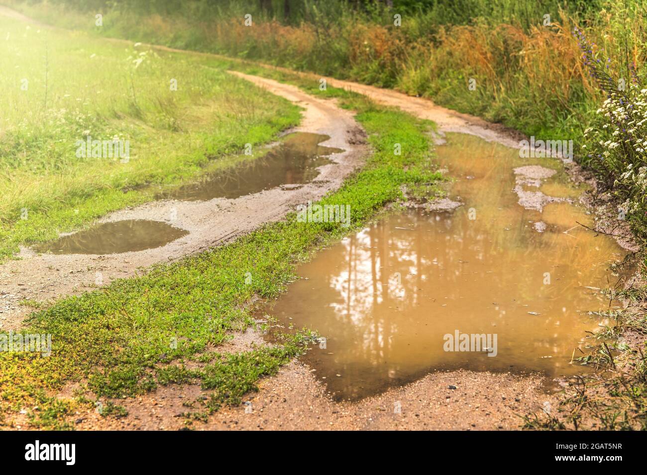 Große Pfützen auf der Straße nach Regen im Sommer. Schlammige Feldstraße mit einer Pfütze in der tschechischen Landschaft. Wasser auf dem Weg. Stockfoto