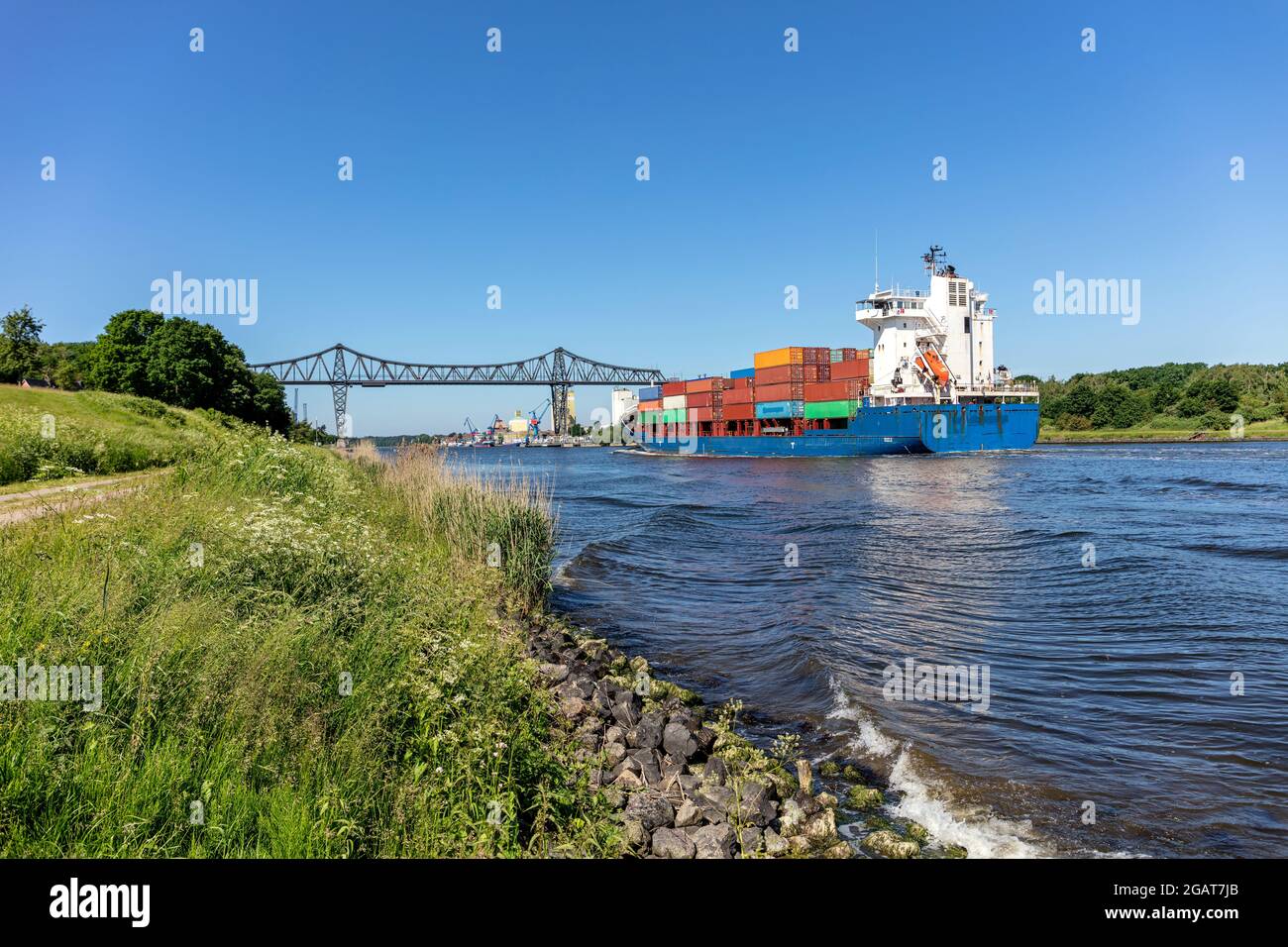 Containerschiff im Nord-Ostsee-Kanal mit der berühmten Rendsburg-Hochbrücke im Hintergrund Stockfoto