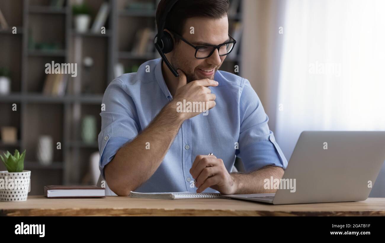 Junger männlicher Student im Headset confer mit Lehrer online Stockfoto