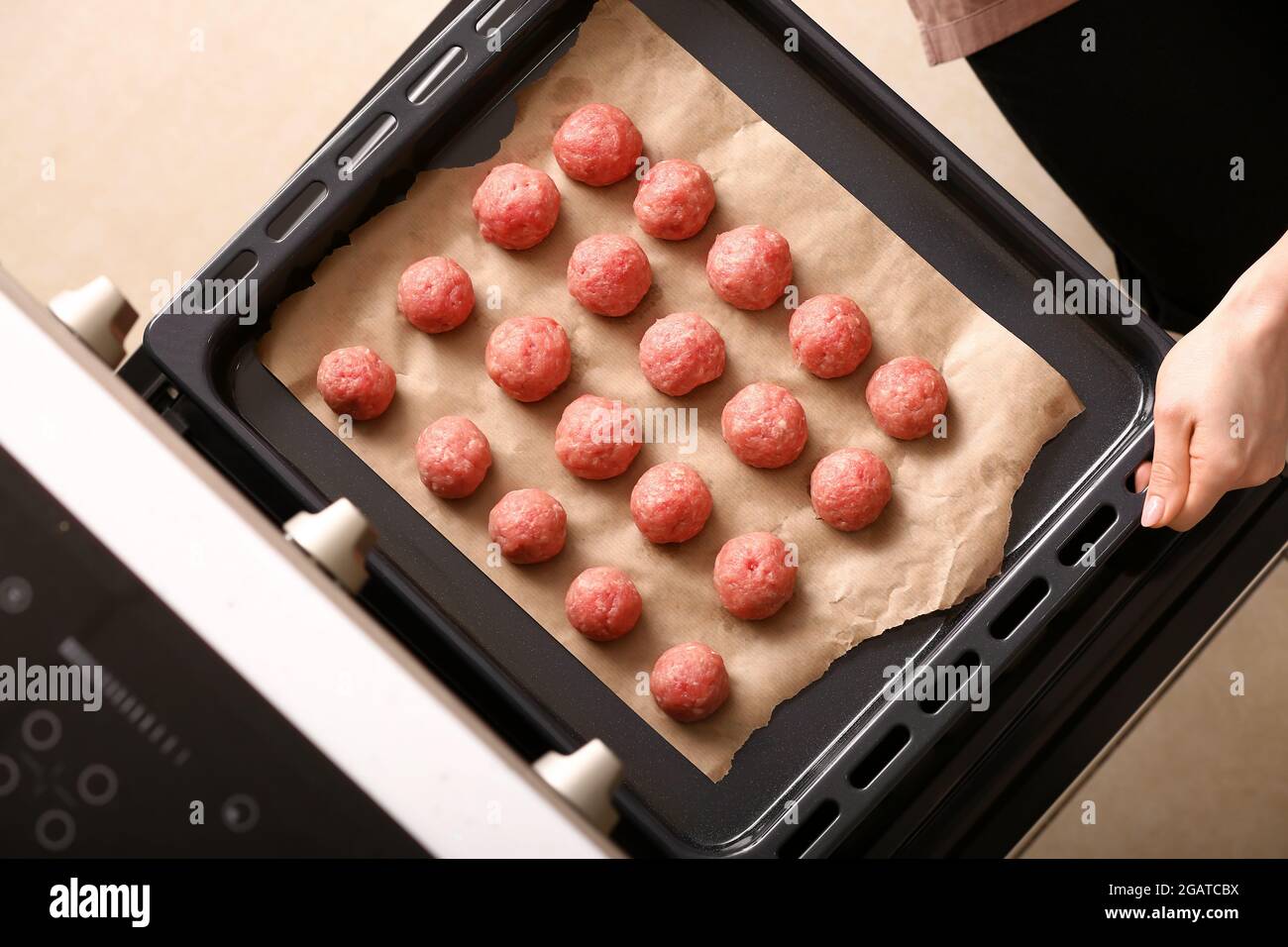 Frau, die Backblech mit rohen Koteletten aus frischem Zopf in den Ofen  legt, Nahaufnahme Stockfotografie - Alamy