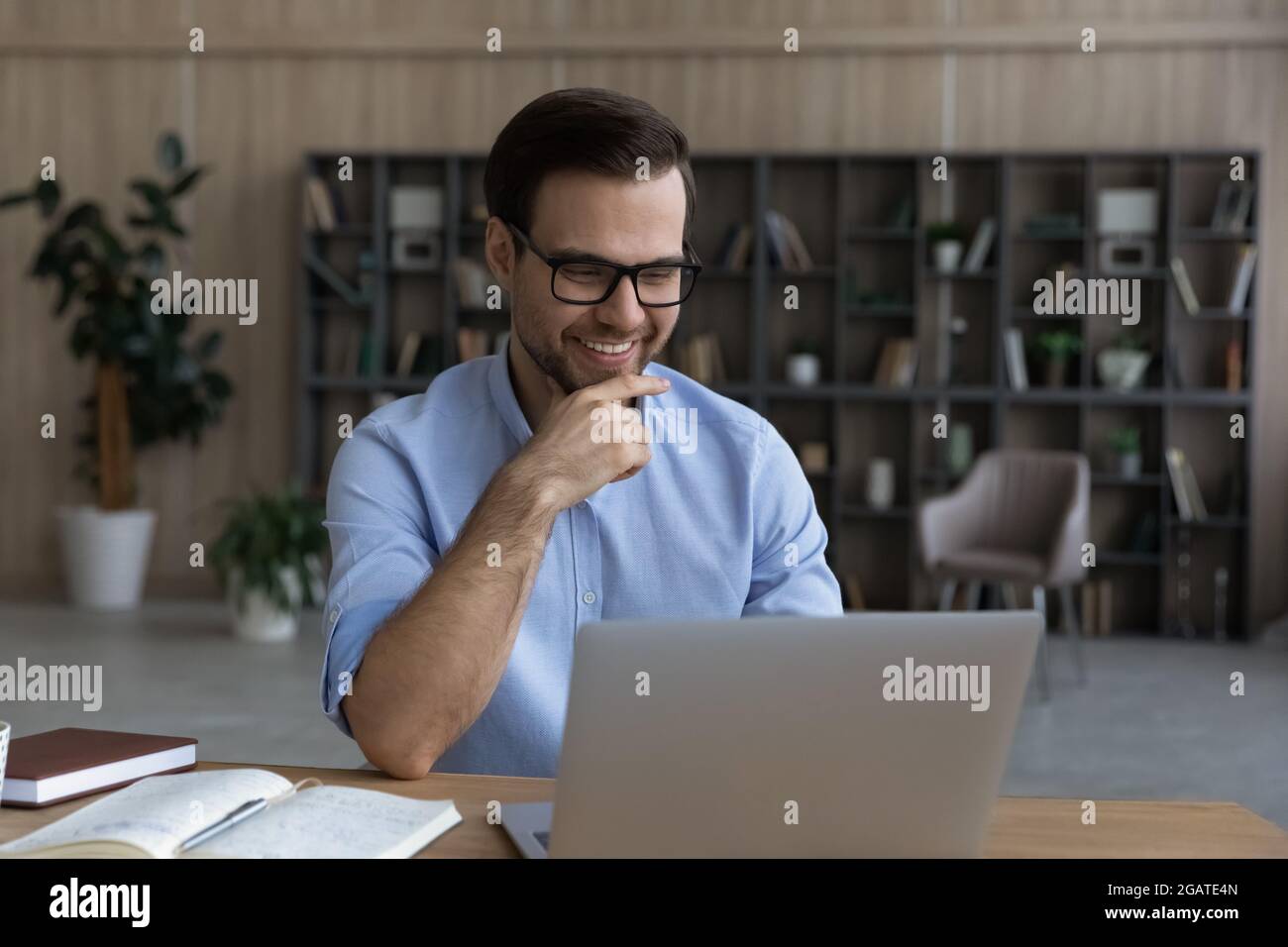 Lächelnder, intelligenter junger Mann sitzt am Laptop im wissenschaftlichen Labor Stockfoto