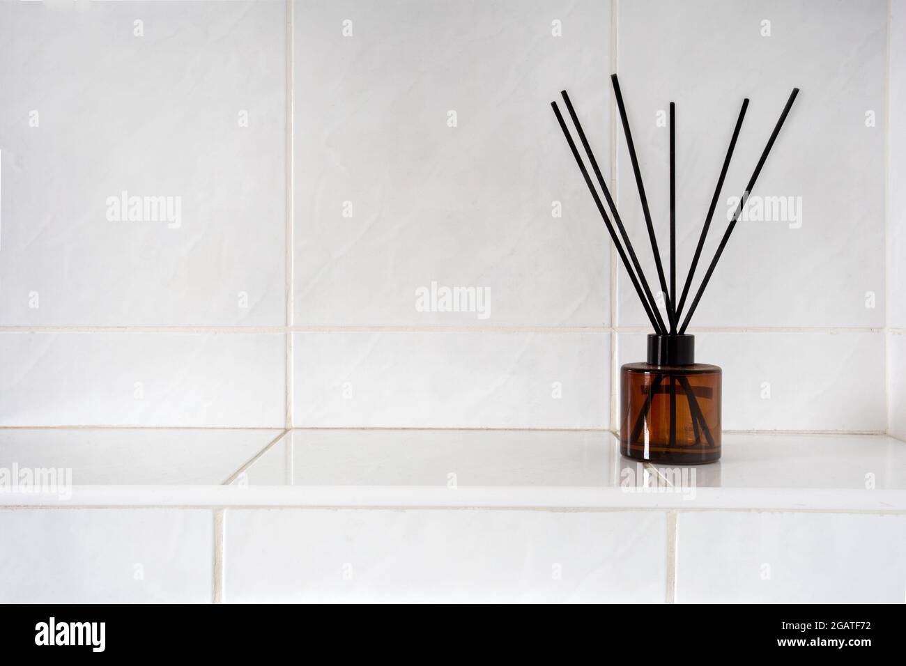 Aromatherapie-Sticks in Glasflasche in Toilette oder Bad in der Nähe von weiß gefliesten Wand mit Kopierraum, Parfüm und Bambus-Luxusprodukt Stockfoto