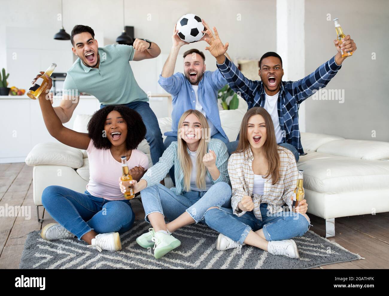 Begeisterte verschiedene Freunde, die Fußball gucken, Fußball halten, Tore  rufen, den Sieg feiern und für ihre Lieblingsmannschaft zu Hause jubeln.  Gruppe von Stockfotografie - Alamy