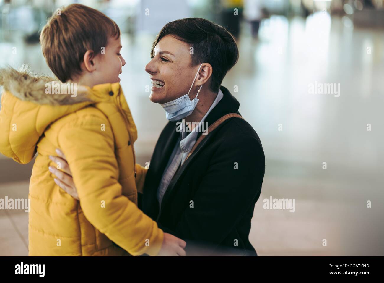 Frau, die ihren Sohn nach einer Pandemie am Flughafen trifft. Sohn ist Mutter und trifft ihr Kind nach langer Trennung während des Corona-Virus-Ausbruchs. Stockfoto