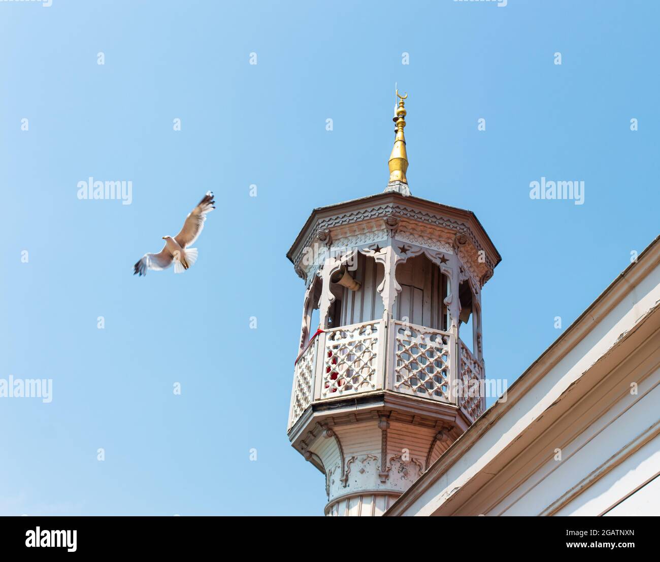 Minarett einer muslimischen Moschee mit Möwe auf dem klaren blauen Himmel Hintergrund. Ein antikes Minarett mit antiken Motiven. Stockfoto