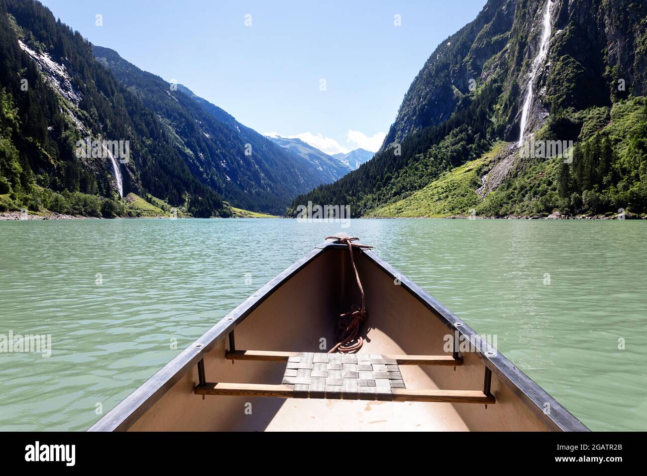 Spitze des Kanus auf Bergsee im Sommer alpine Landschaft, mit zwei Wasserfällen im Hintergrund. Stillup Stausee, Stillup Lake, Österreich, Tirol Stockfoto