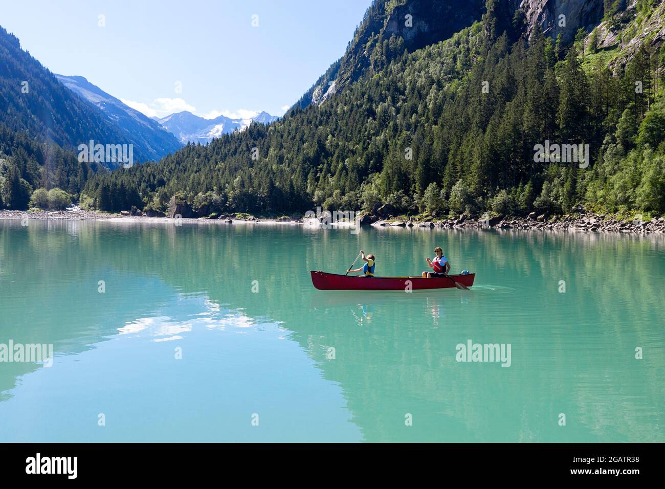 Mutter und Sohn sitzen im Kanu und reiten auf dem Bergsee in der sommerlichen Alpenlandschaft. Stillup Stausee, Stillup Lake, Österreich, Tirol Stockfoto