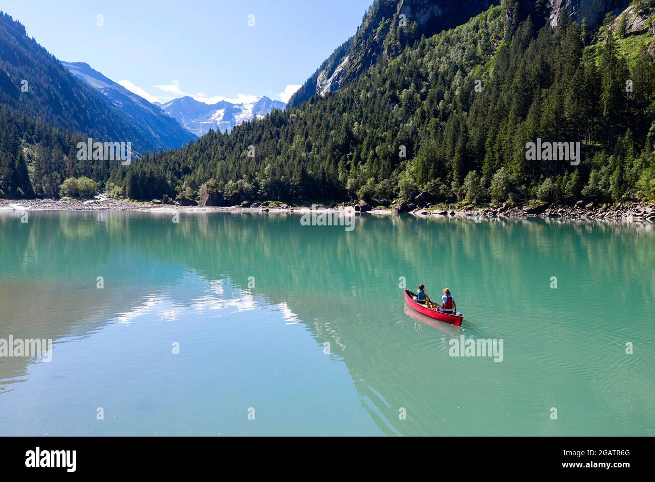 Mutter und Sohn sitzen im Kanu und reiten auf dem Bergsee in der sommerlichen Alpenlandschaft. Stillup Stausee, Stillup Lake, Österreich, Tirol Stockfoto