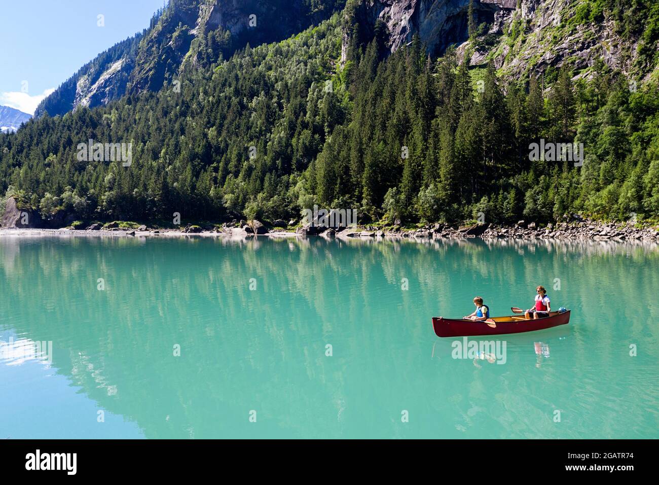 Mutter und Sohn sitzen im Kanu und reiten auf dem Bergsee in der sommerlichen Alpenlandschaft. Stillup Stausee, Stillup Lake, Österreich, Tirol Stockfoto