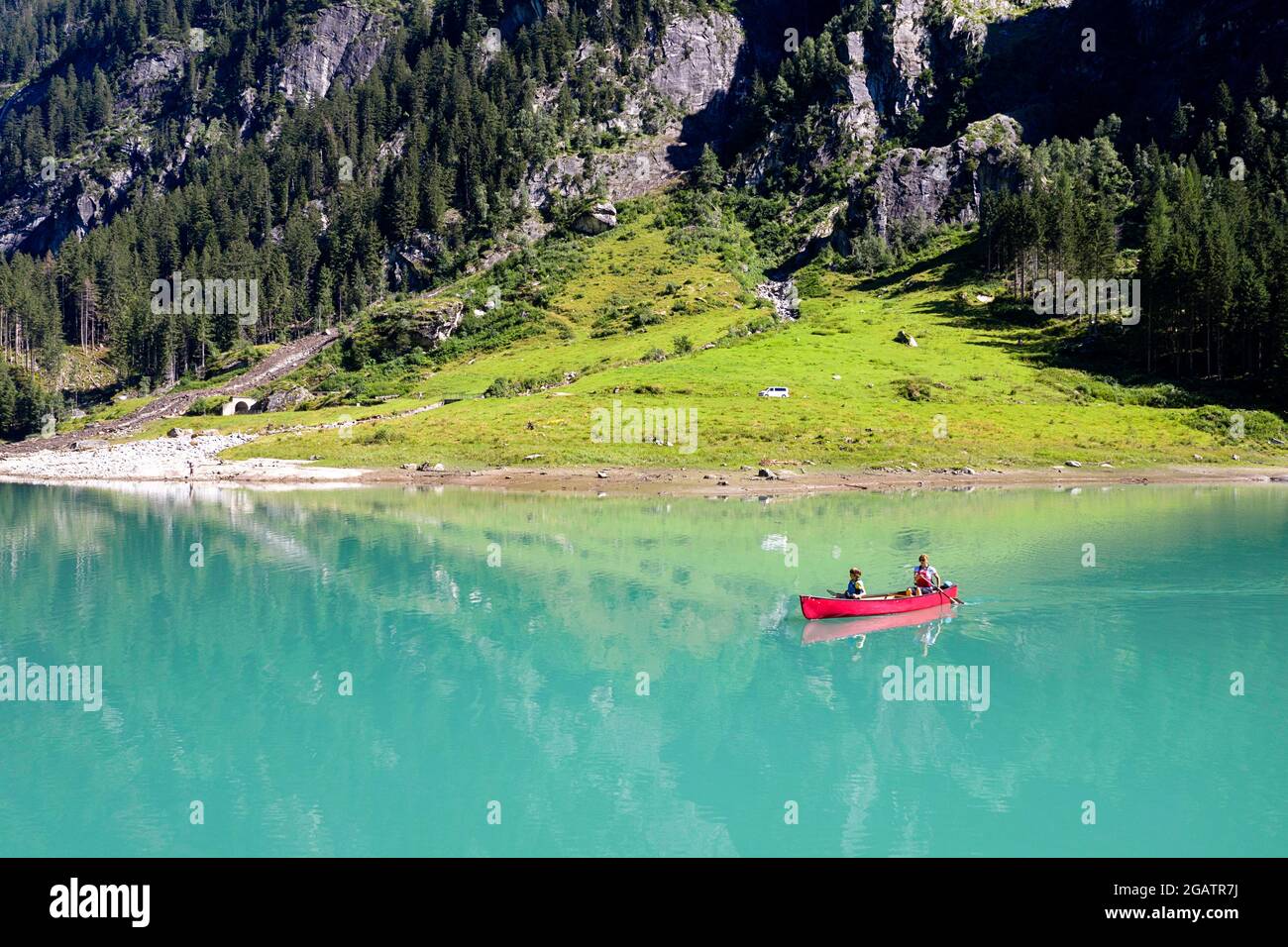 Mutter und Sohn im Kanu fahren auf Bergsee im Sommer alpine Landschaft mit Wasserfall im Hintergrund. Stillup Stausee, Stillup Lake, Österreich, Tirol Stockfoto