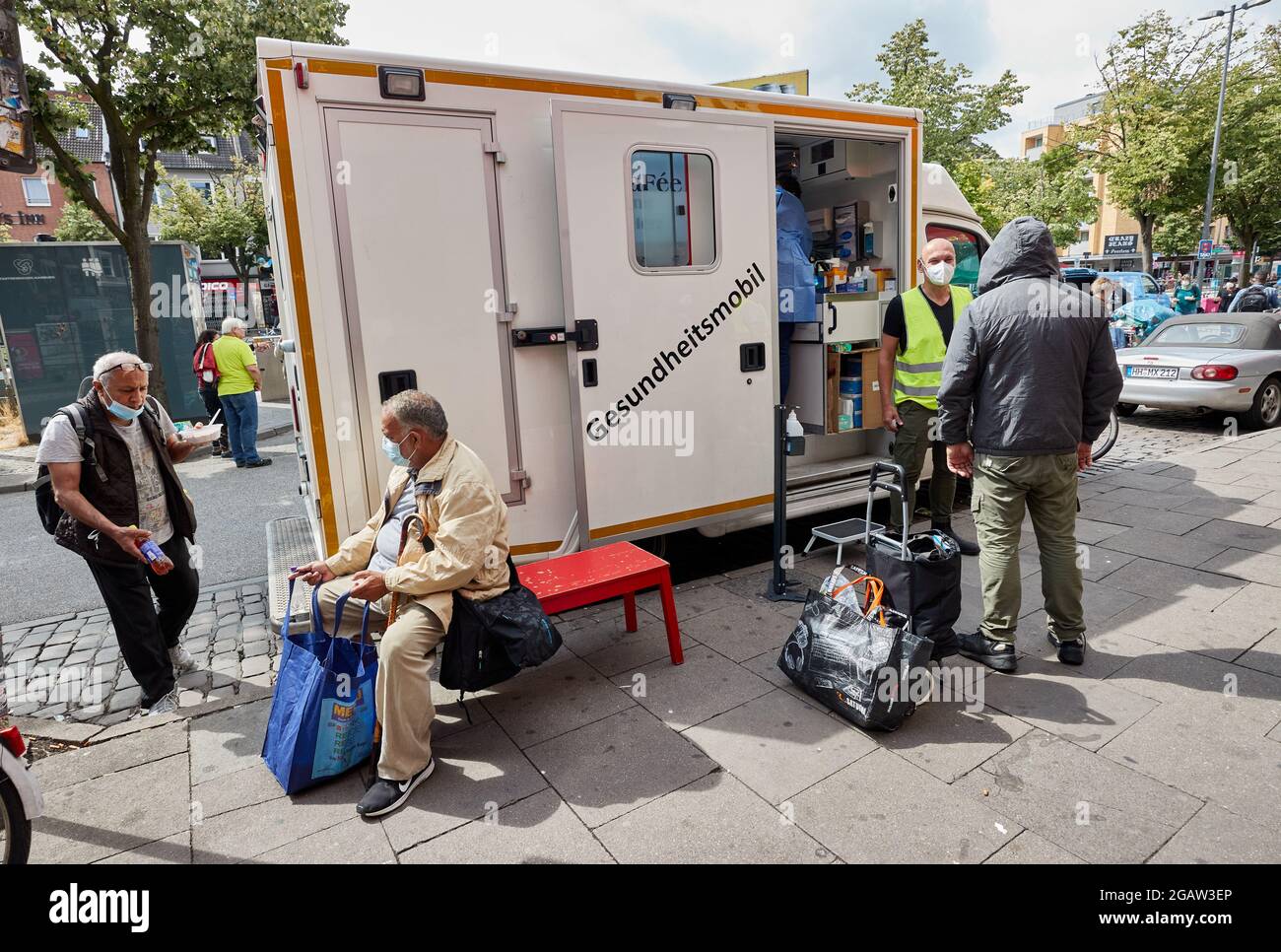 Hamburg, Deutschland. August 2021. Tom Möller (2. Von rechts mit gelber  Weste), Fahrer und Sozialarbeiter, spricht mit einem Obdachlosen (r) vor  dem Health Mobile auf der Reeperbahn. Das Health Mobile, das vom