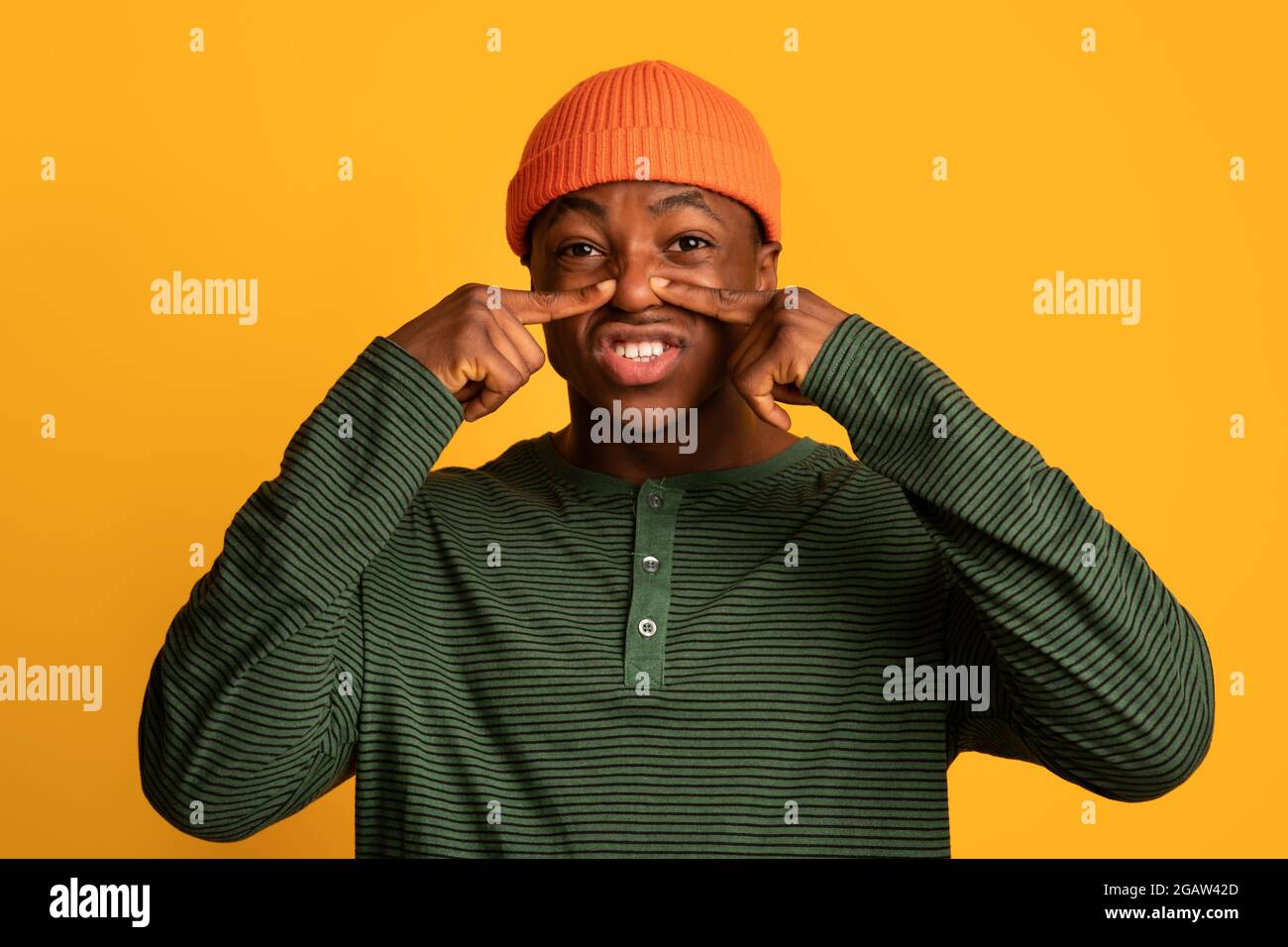 Schlechter Geruch. Lustiger Junger Schwarzer Mann, Der Seine Nase Mit Zwei Fingern Zumacht, Angewiderter Afroamerikanischer Kerl In Orange Hat Sich Durch Schrecklichen Geruch Genört, Stockfoto