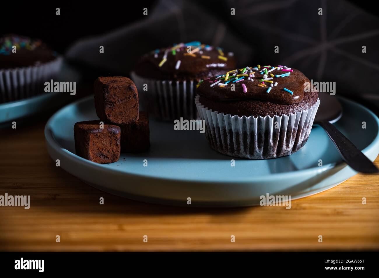 Geburtstagskuchen. Leckere Cupcakes aus Schokolade mit Creme und farbigen Streuseln. Süßer, köstlicher Desserttrüffel und Süßigkeiten auf einem Teller. Weißer Hintergrund wi Stockfoto