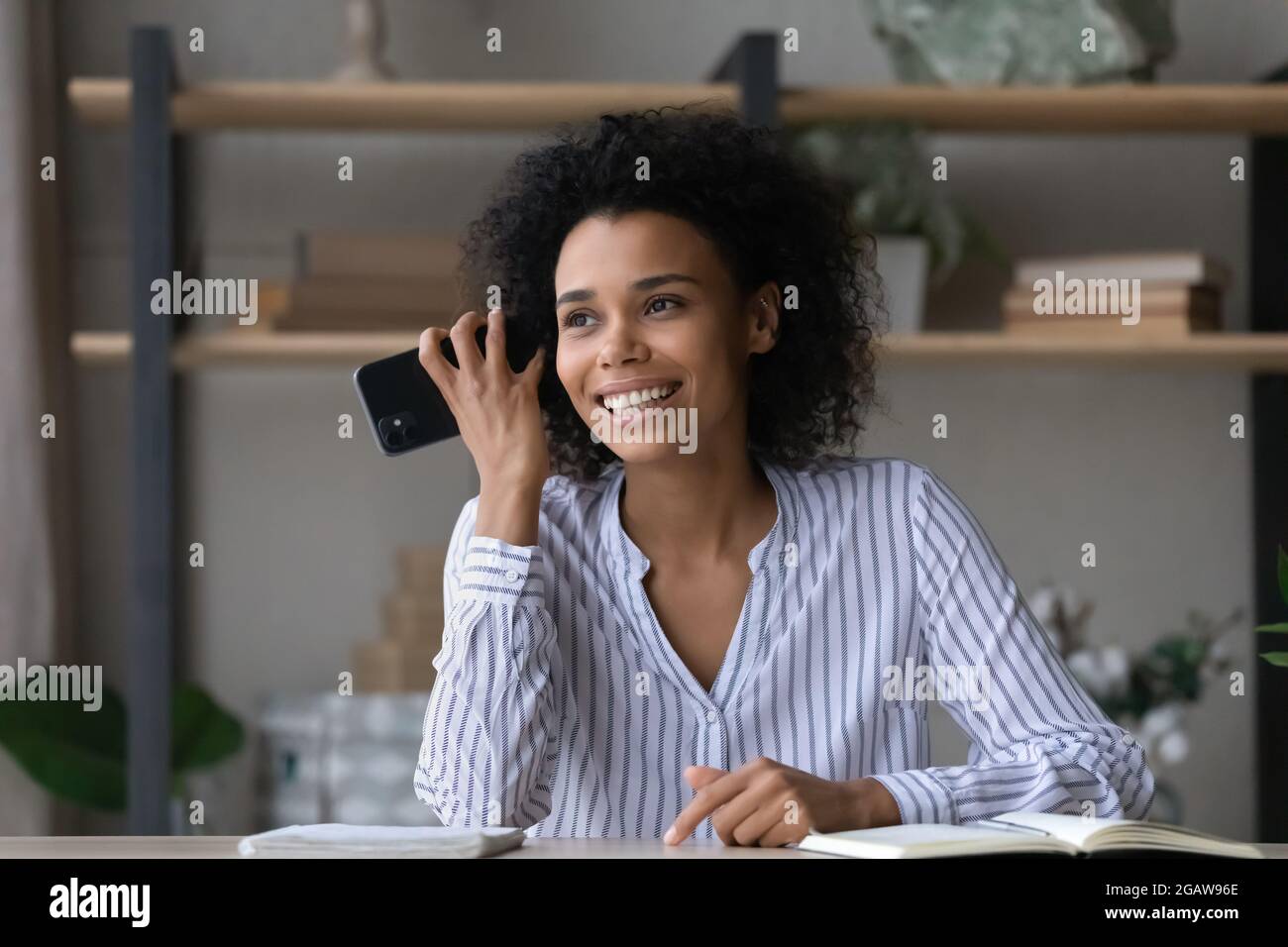 Lächelnde afroamerikanische Frau hört sich die Audiobotschaft auf der Zelle an Stockfoto