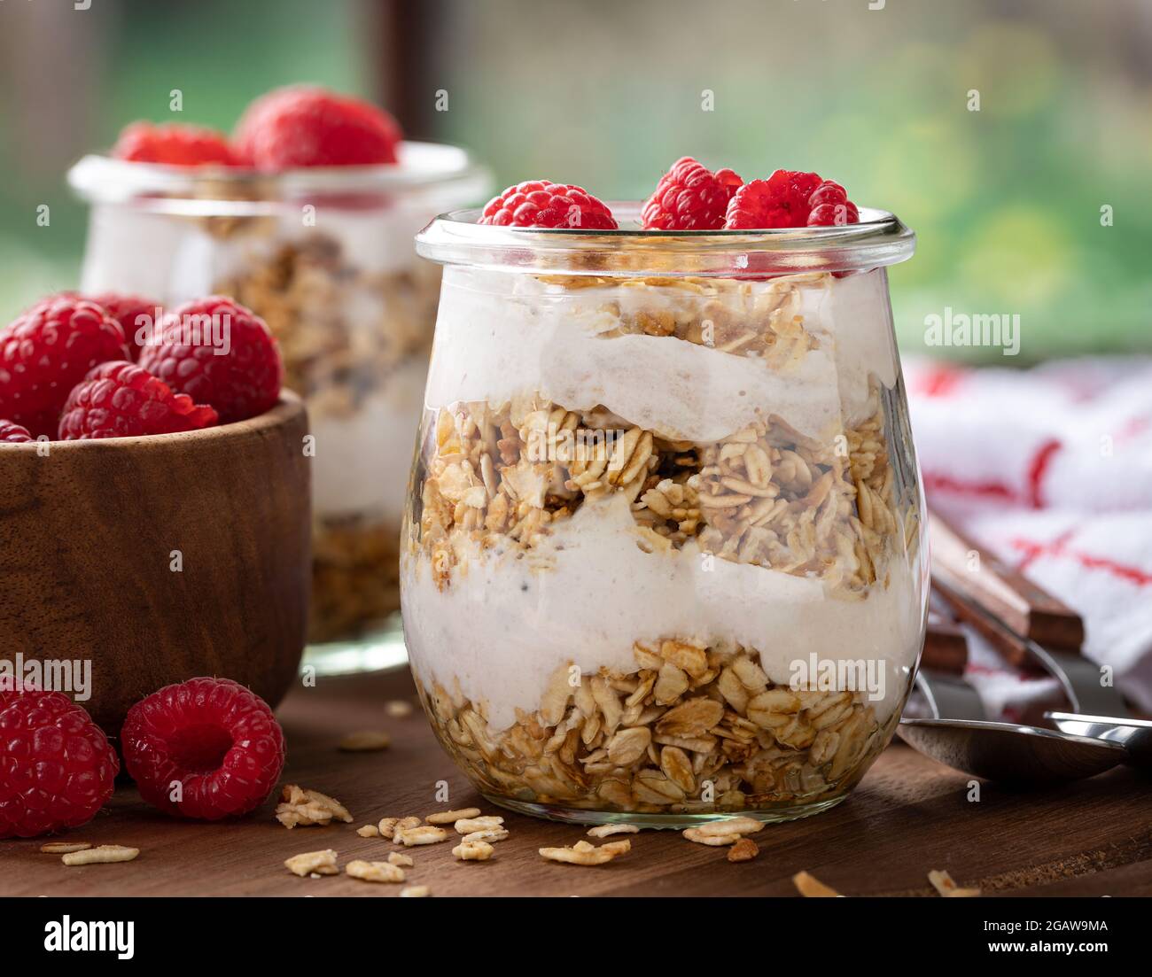 Nahaufnahme eines Granola-Parfait mit Joghurt und frischen Himbeeren auf einem Holztisch Stockfoto
