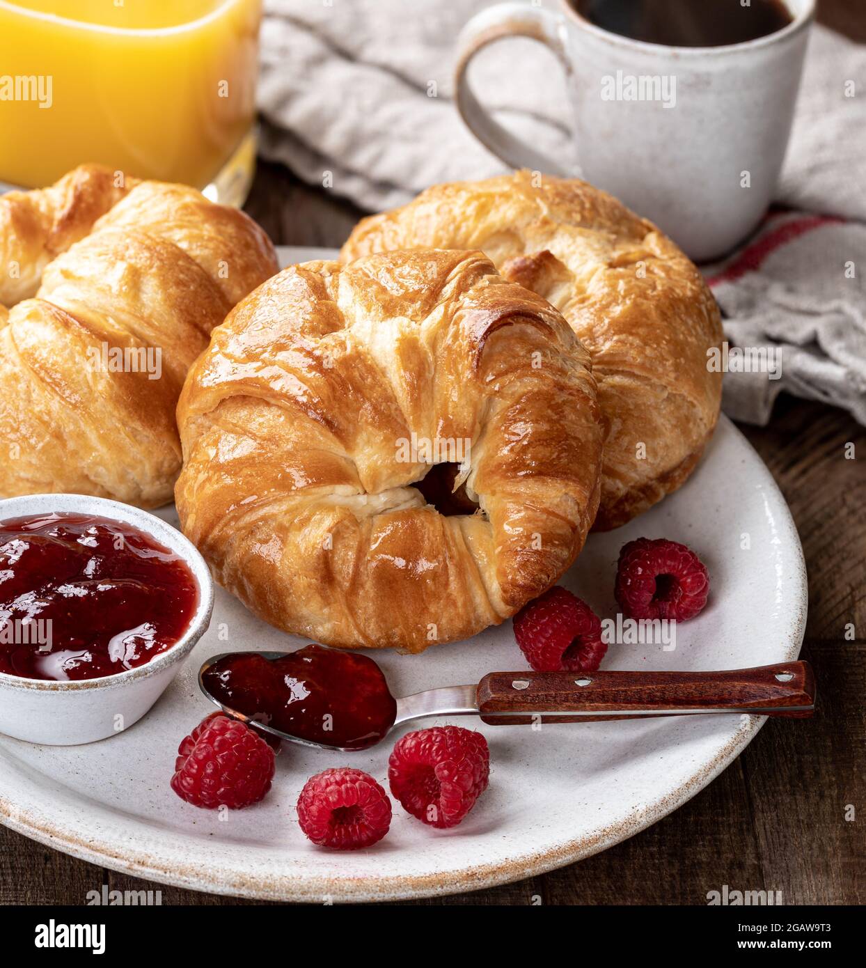 Croissants mit Himbeerkonfitüre und frischen Himbeeren auf einem Teller Stockfoto