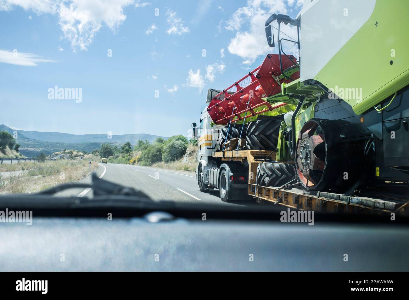 Harvester mit Schwerlast-LKW. Blick vom Innenraum des Autos beim Überholen Stockfoto