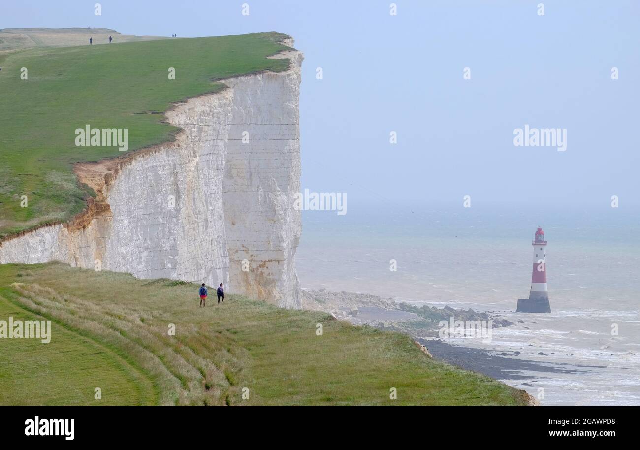 Spaziergänger auf dem South Downs Way, vorbei am Leuchtturm in Beachy Head, East Sussex, Großbritannien Stockfoto