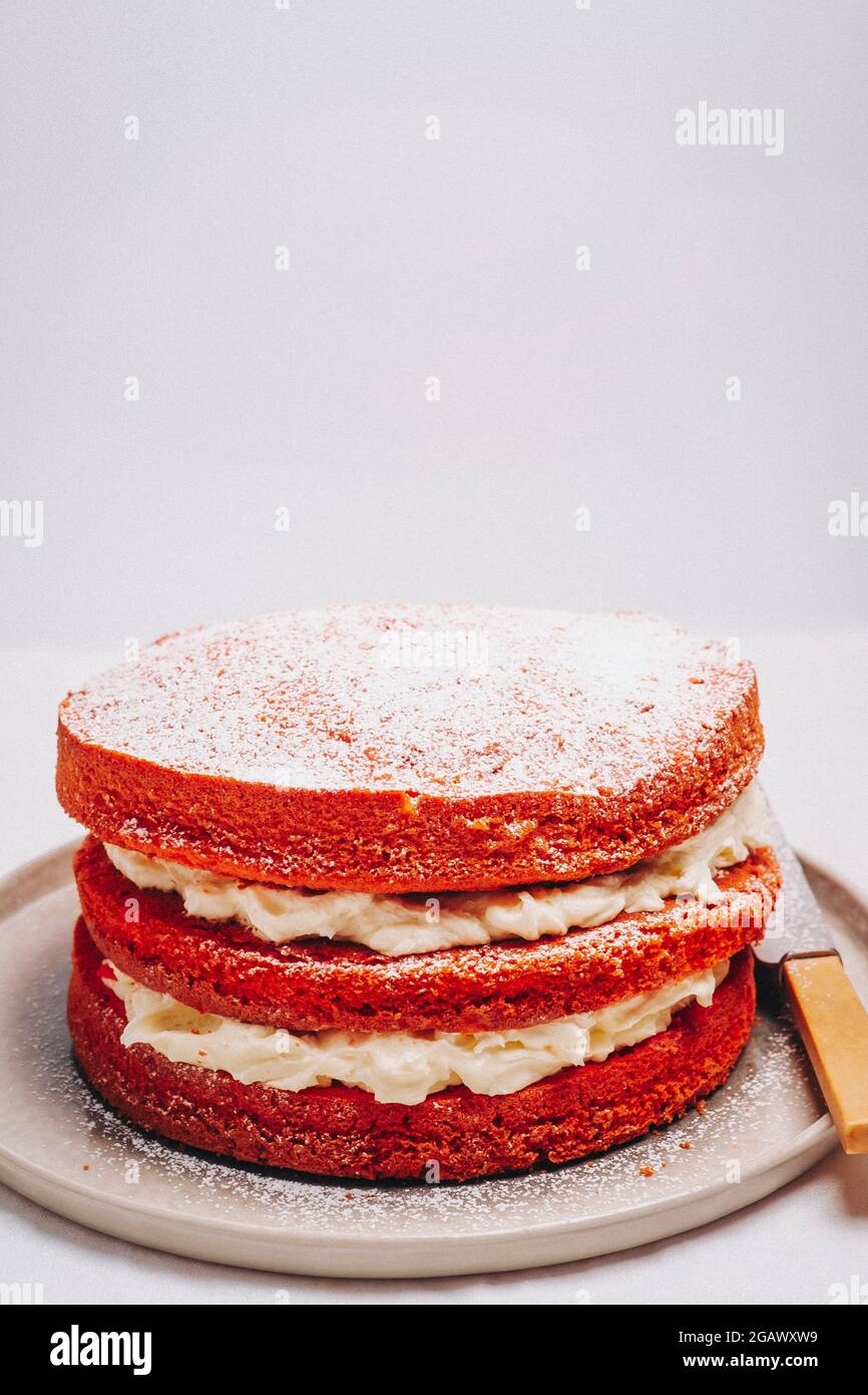 Victoria Sponge Kuchen gefüllt mit Schlagsahne auf einem Teller mit einem Messer auf einem Tisch – FOODPIX WEISS, COPYSPACE Stockfoto