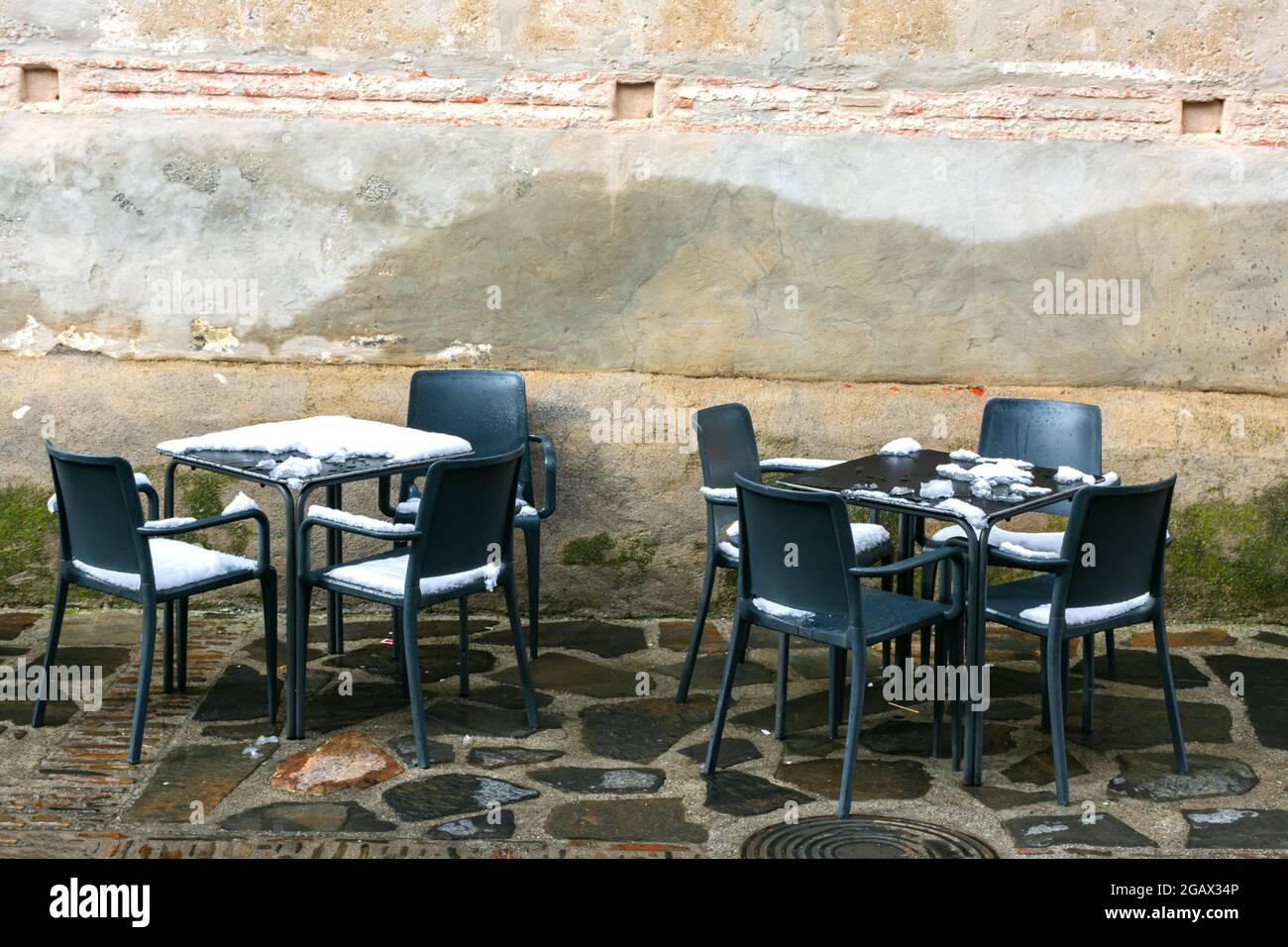 Tische und Stühle auf einer schneebedeckten Terrasse einer Bar. Stockfoto