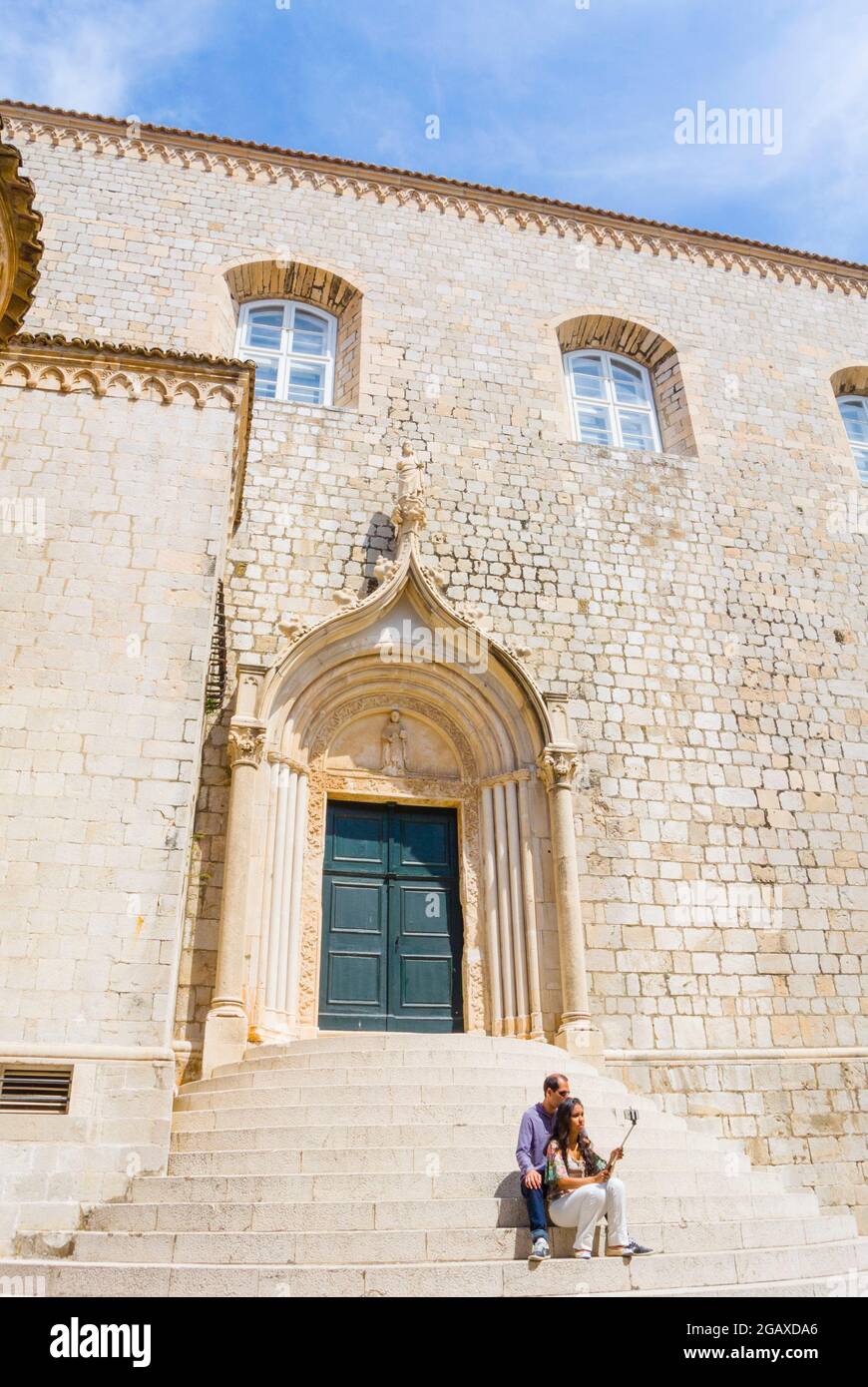 Touristisches Paar, das ein Selfie mit einem Selfie-Stick macht, auf den Stufen des Crkva sv. Dominika, Grad, die Altstadt, Dubrovnik, Dalmatien, Kroatien Stockfoto