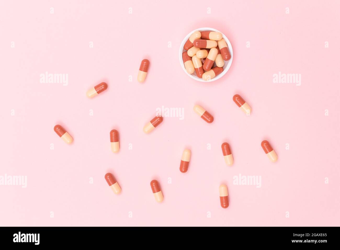 Globale Pharmaindustrie und Medizinprodukte - farbige Pillen oder Kapseln auf rosa Hintergrund verstreut Stockfoto