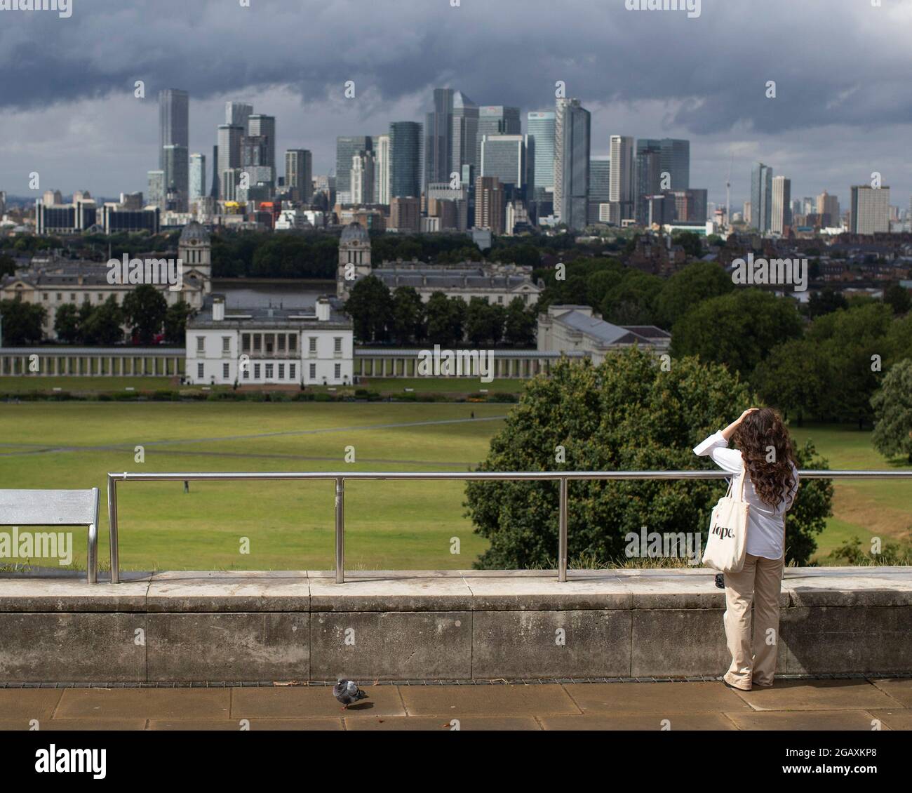 30/07/2021. London, Großbritannien. Ein Mitglied der Öffentlichkeit blickt während eines Regensturms im Greenwich Park im Südosten Londons auf Canary Wharf. Phot Stockfoto