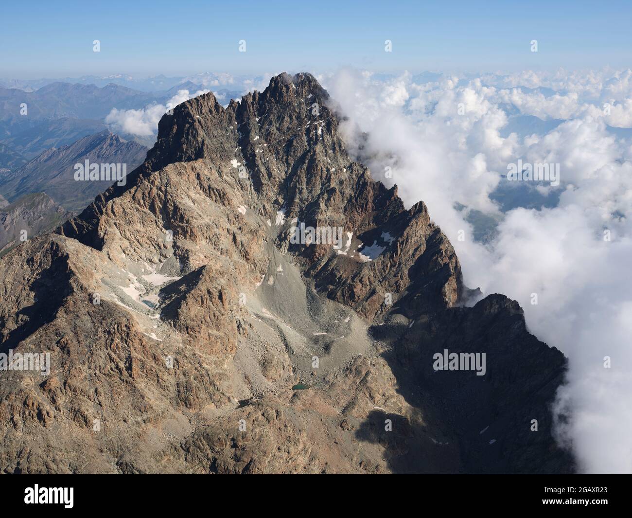 LUFTAUFNAHME. Südliche, zerklüftete Felswand des Monte Viso (3841m) mit Wolken östlich über der Po-Ebene. Provinz Cuneo, Piemont, Italien. Stockfoto