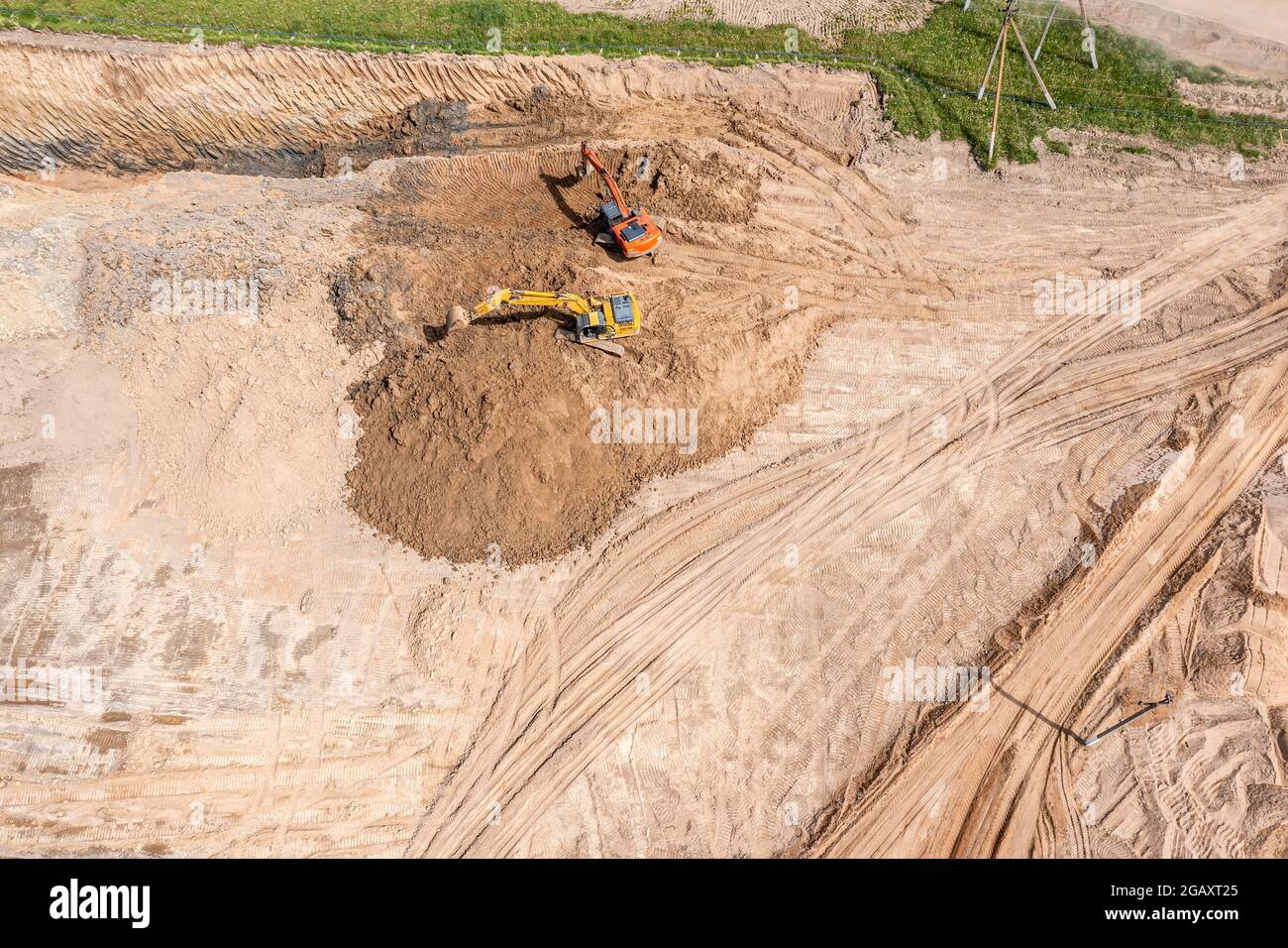 Schwere gelbe und orange Bagger bewegen den Boden auf der Baustelle. Luftaufnahme von oben Stockfoto