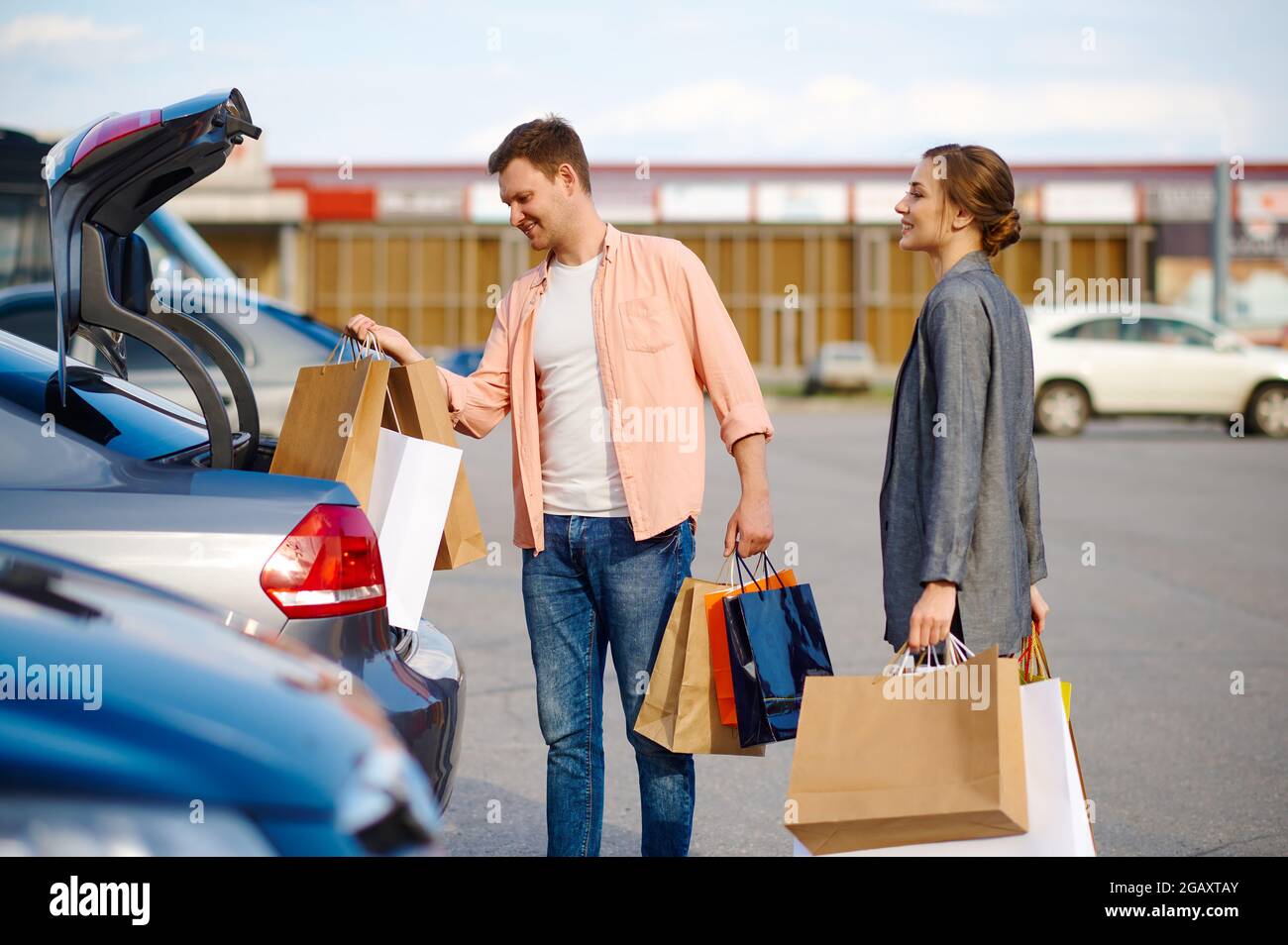 Das Paar legt seine Einkäufe im Kofferraum auf dem Parkplatz ab Stockfoto
