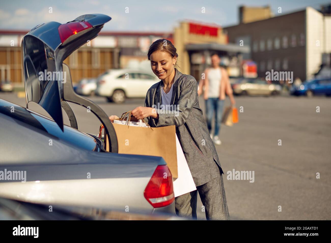 Frau legt ihre Einkäufe in den Kofferraum auf den Parkplatz Stockfoto