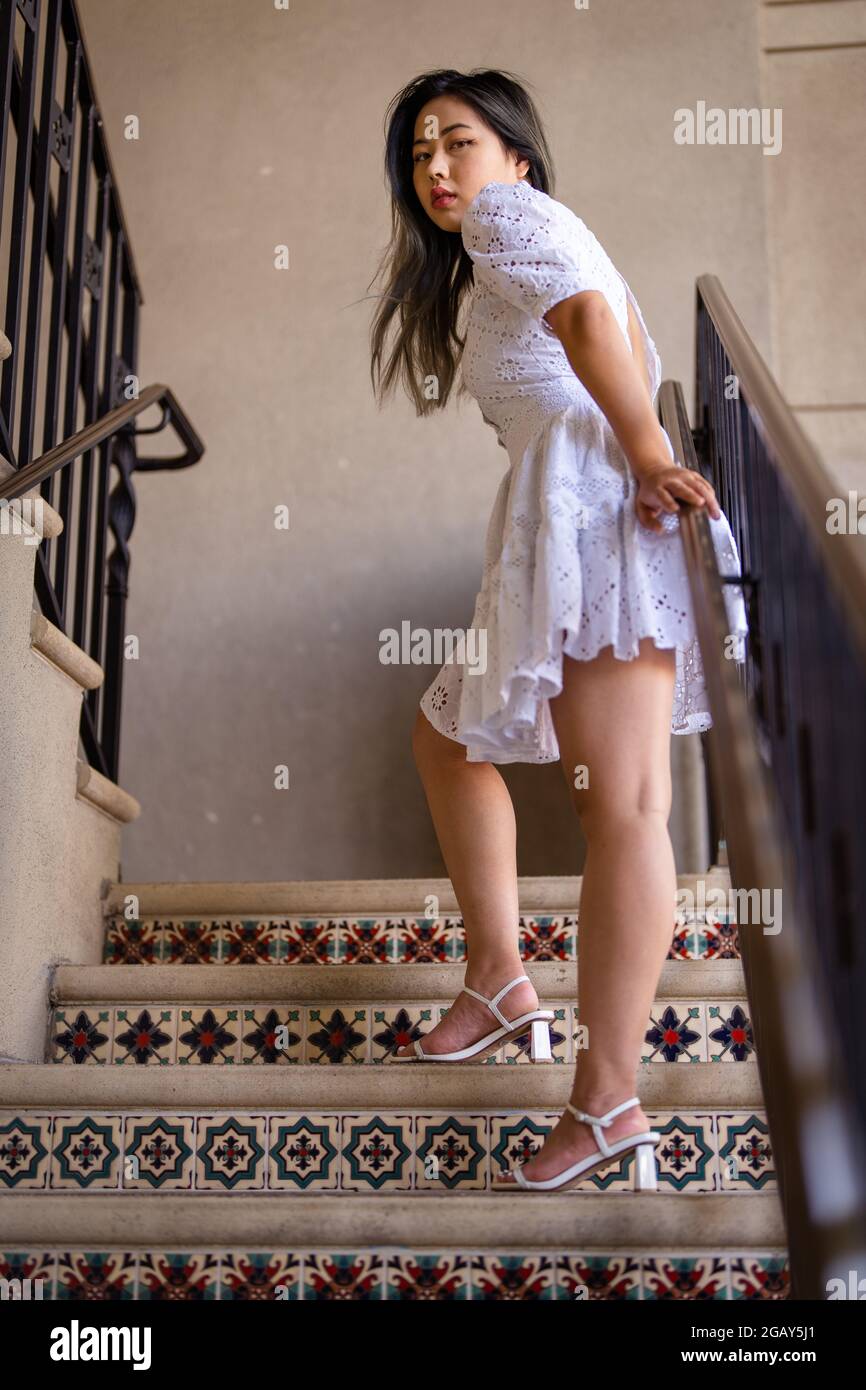 Porträt einer schönen asiatischen Frau, die im Sommerkleid auf einer Treppe steht Stockfoto