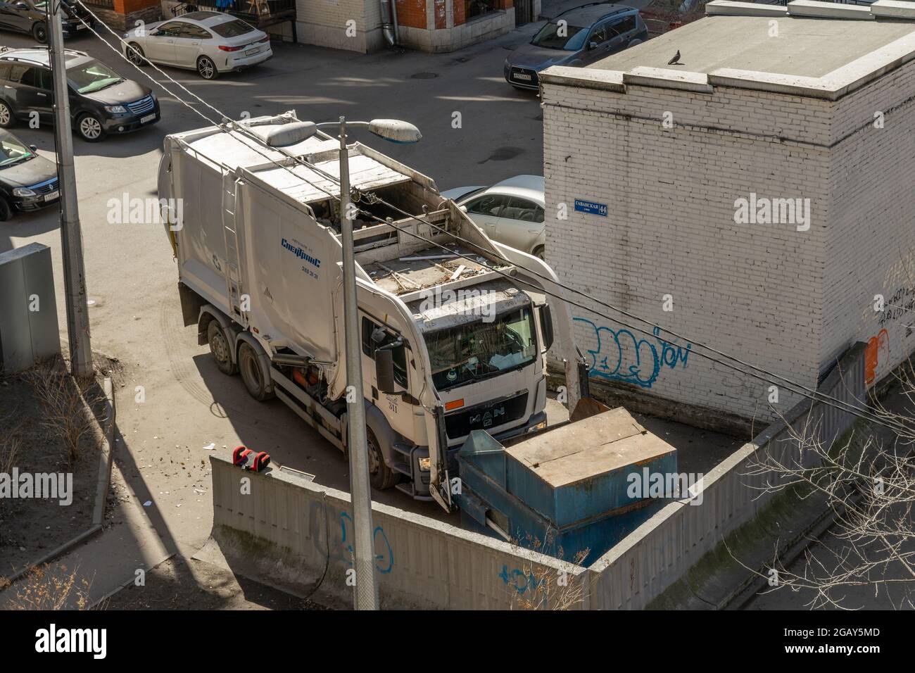 Heil Environmental MAN TGS Automated Front Load Garbage Truck picking large Metal Garbage Container, High angle view, St. Petersburg, Russland Stockfoto
