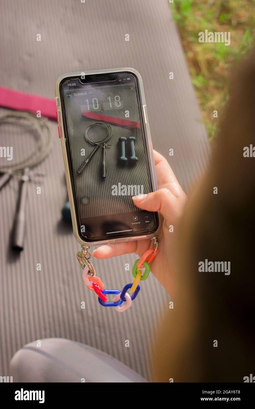 Vertikales Bild einer Frau, die in sozialen Medien teilhat ein Foto von Zubehör, das für den Pilates-Trainingskurs benötigt wurde. Pilates Outdoor 2021. Stockfoto