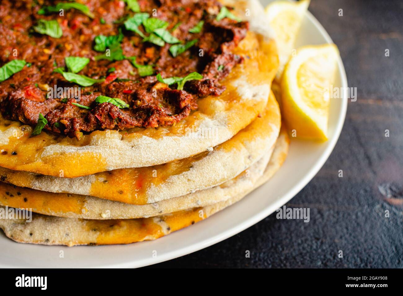 Nahaufnahme Ansicht von türkischem Lahmacun serviert mit Zitronenkeilchen: Türkische Fladenbrote mit gewürztem Hackfleisch garniert und mit gehackten Minzblättern garniert Stockfoto