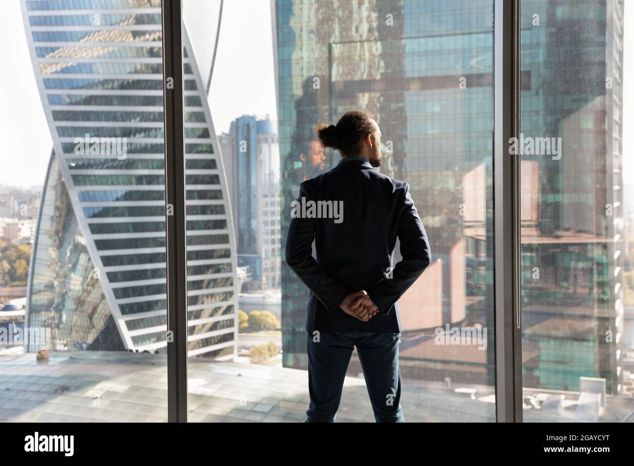 Selbstbewusster junger afroamerikanischer Geschäftsmann im Anzug, der neben dem Fenster steht. Stockfoto