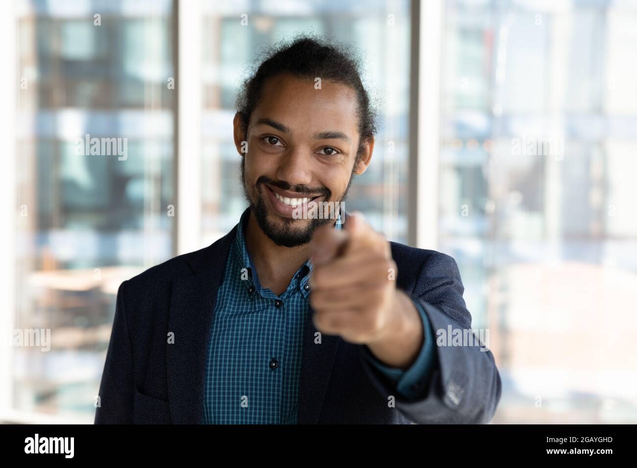 Lächelnder, freundlicher junger afrikanischer Geschäftsmann, der mit dem Finger auf die Kamera zeigt. Stockfoto