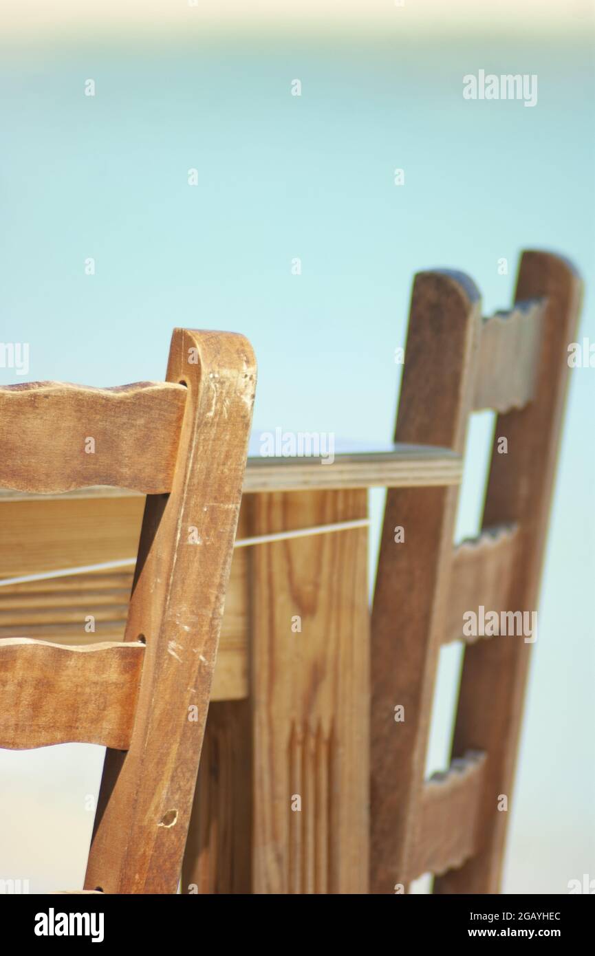 Griechische Tavernenmöbel. Nahaufnahme der traditionellen Tische und Stühle im Restaurant. Vertikale Seitenansicht. Unscharfer Hintergrund. Speicherplatz kopieren. Stockfoto