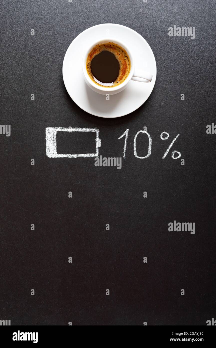 Tasse Kaffee und eine Anzeige entladene Batterie auf schwarzem Hintergrund, Platz zum Kopieren. Aufladung, Kaffeeenergie und Heiterkeit Konzept Stockfoto