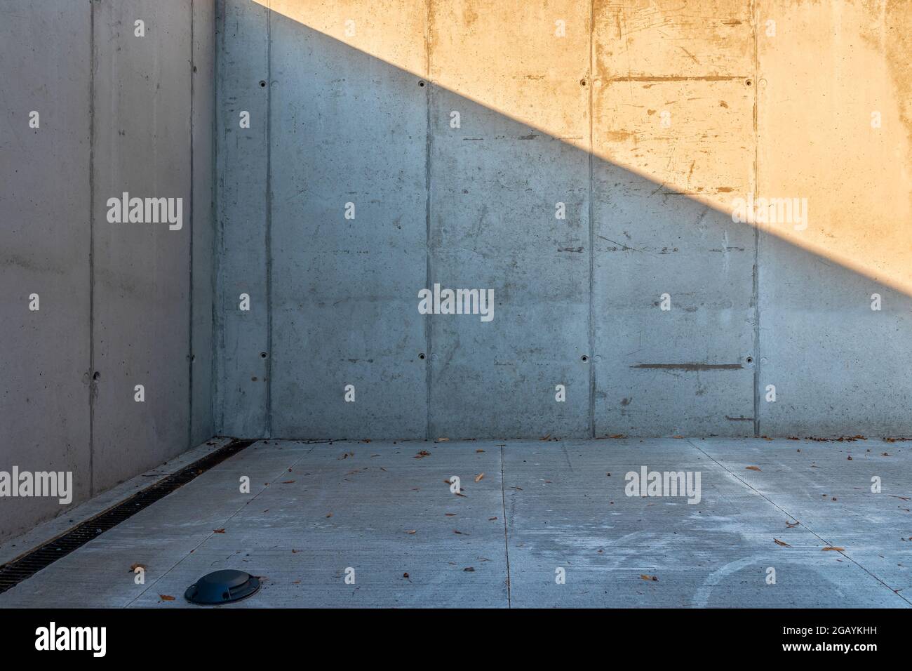 Leere Ecke außerhalb des Gebäudes, Wände und Boden aus Beton. Linearer Abfluss parallel zur Wand. Moderne Architektur. Stockfoto