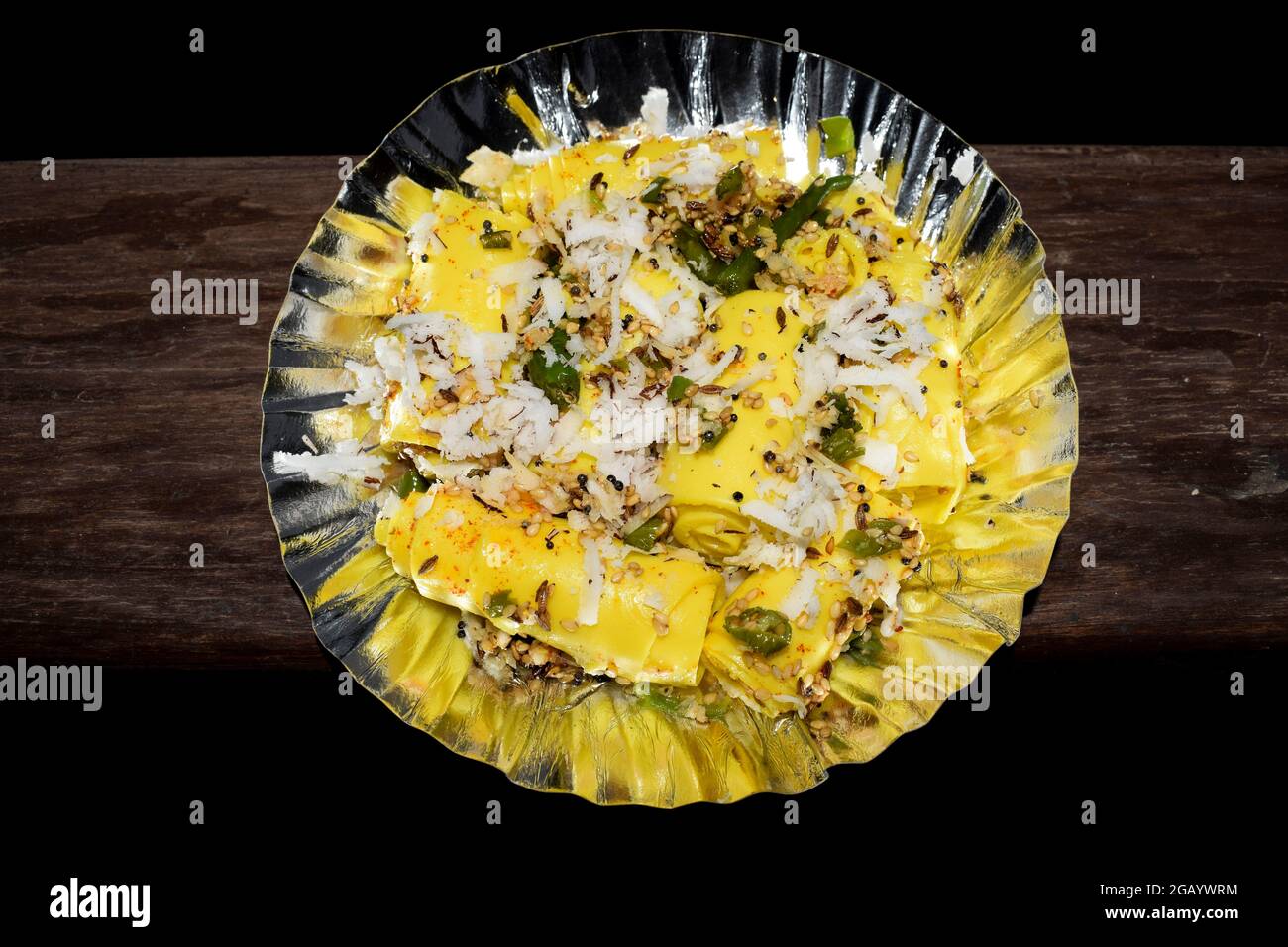 Khandvi ein traditionelles und authentisches Gujarati-Gericht, das als herzhafte Snacks serviert wird. Temperiert und garniert mit geriebener Kokosnuss, grünem Chilly und Sesam Stockfoto