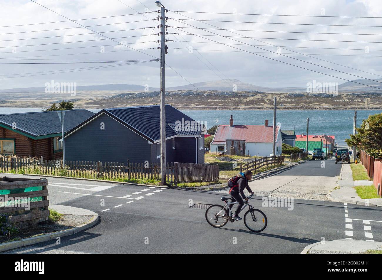 Ein einheimischer Junge radelt in Port Stanley, Falkland Islands, entlang einer Straße Stockfoto