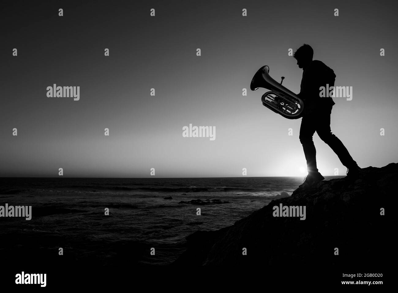 Silhouette eines Musikers mit einer Tuba am Meer. Schwarzweiß-Foto. Stockfoto
