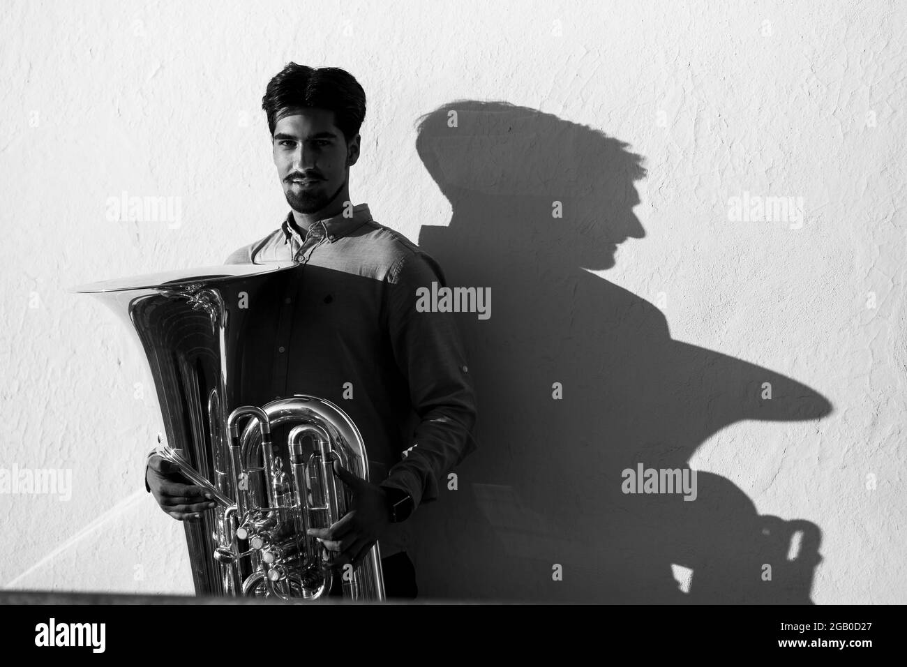 Ein Musiker mit einer Tuba in der Nähe der Wand. Schwarzweiß-Foto. Stockfoto